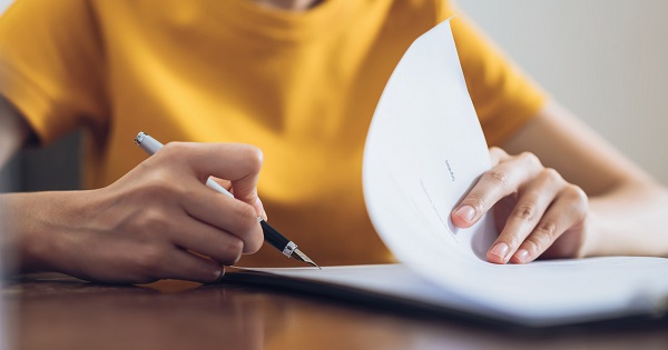 Woman signing document and hand holding pen putting signature at paper, order to authorize their rights.